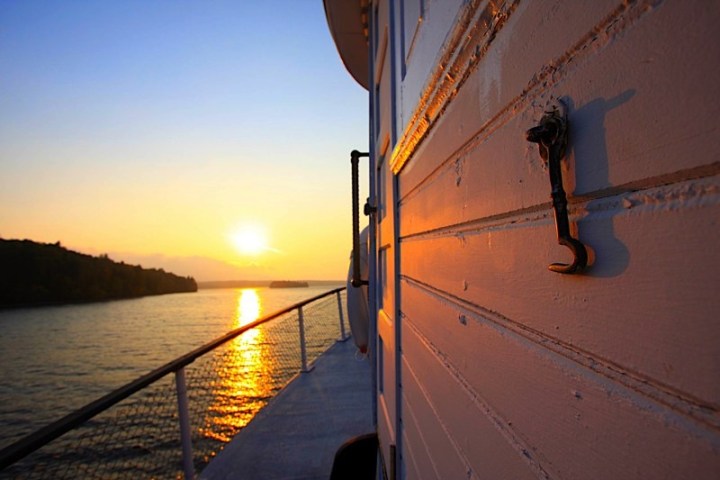 Sunset view from a boat deck with wooden wall and ocean in the background.