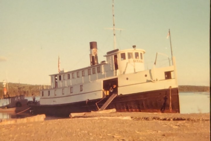 A vintage ferry docked by a calm lake on a clear day.